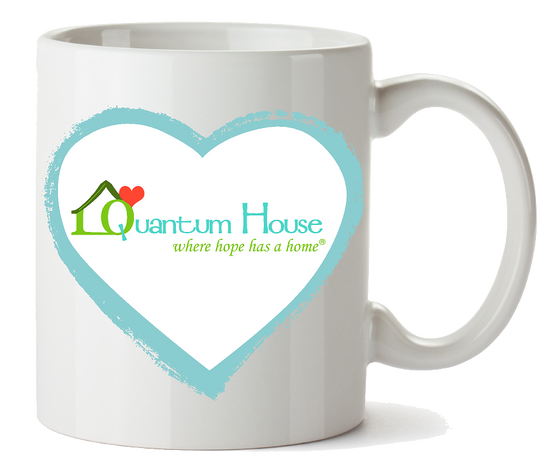 White coffee mug with a blue heart and Quantum House logo promoting support for families in Palm Beach County through artist collaboration